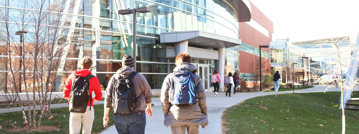 Three students with backpacks pictured walking outside on campus.