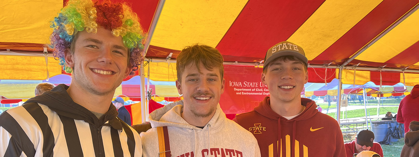 Students smile at an MSE Gold event. One is wearing a clown wig.